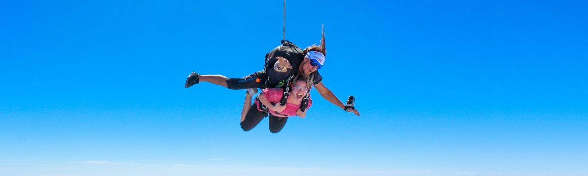 Luke Church skydiving with a student who is wearing a pink shirt.