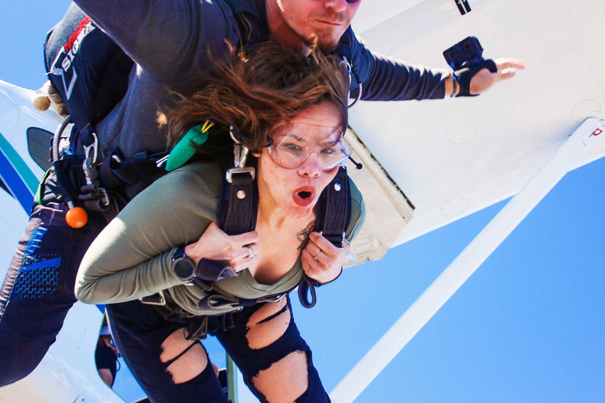Tandem student taking the leap out of the Skydive STL airplane with a look of excitement
